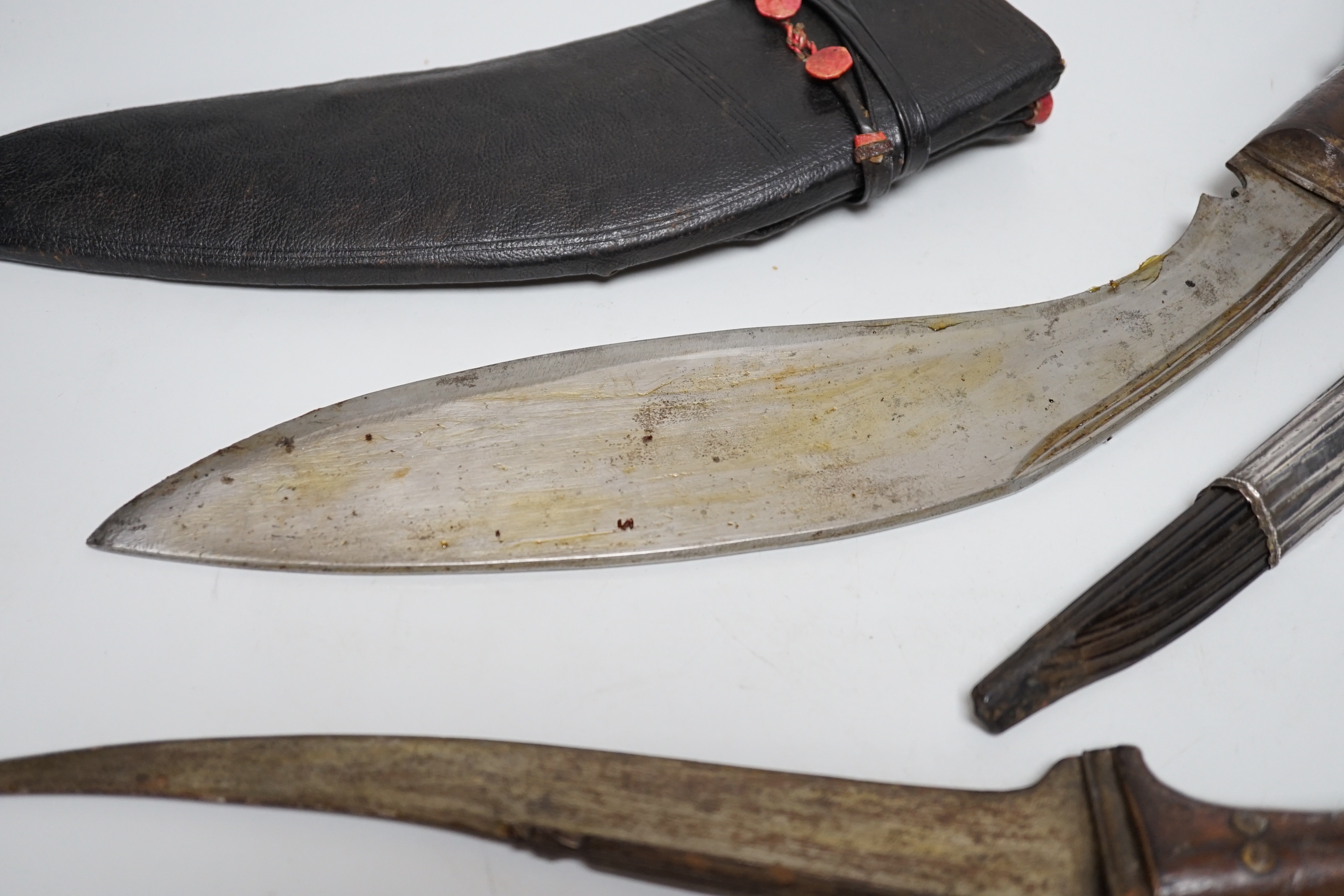 Two Sinhalese daggers and a kukri, a silver inlaid Kirichchiya dagger, together with another in a scabbard with a long pin, another dagger with a wooden handle, a head of a brass inlaid iron pole arm, a George V 1897 pat